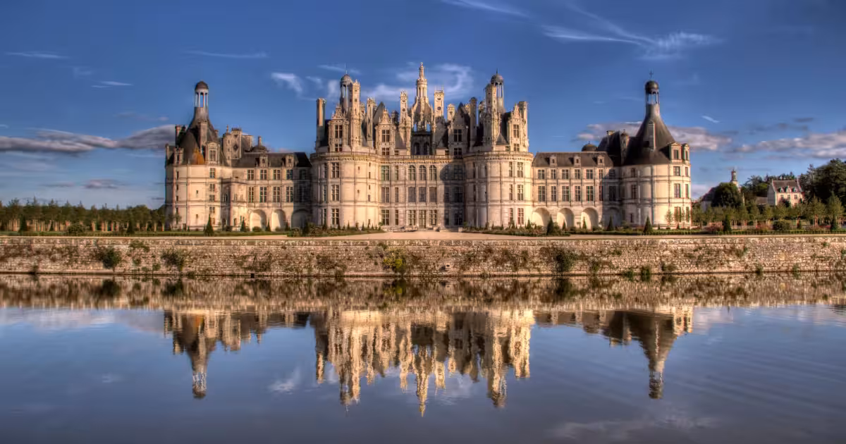 Ch&acirc;teau de Chambord reflected in Loire River waters at golden hour.