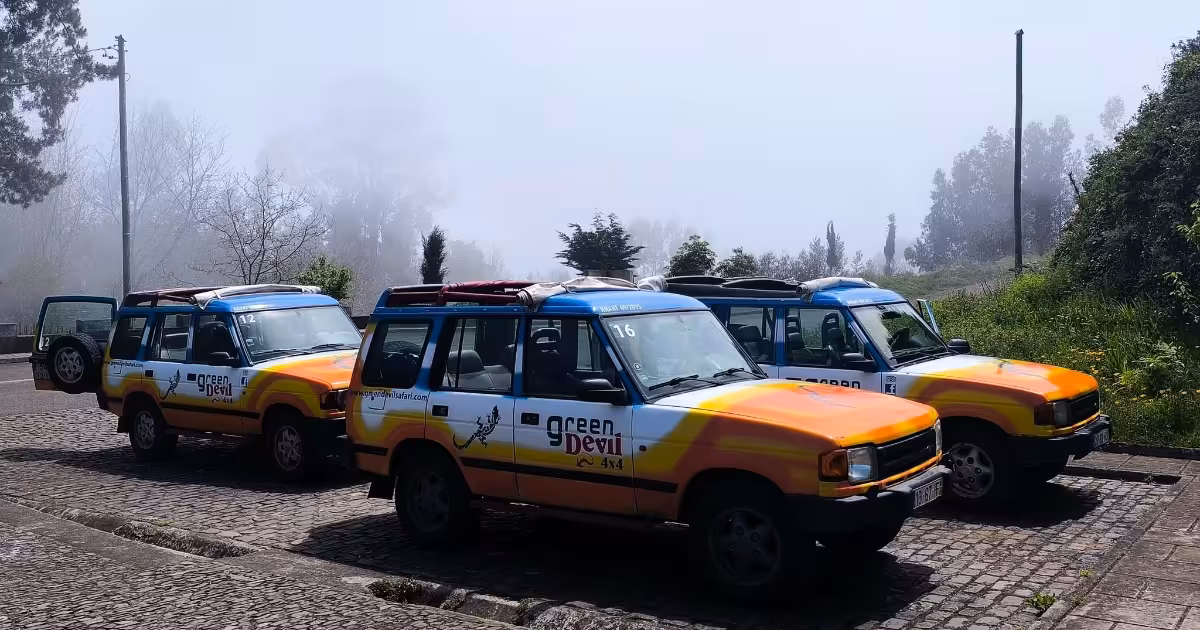 Open-top jeep navigating a steep misty mountain road in Madeira.
