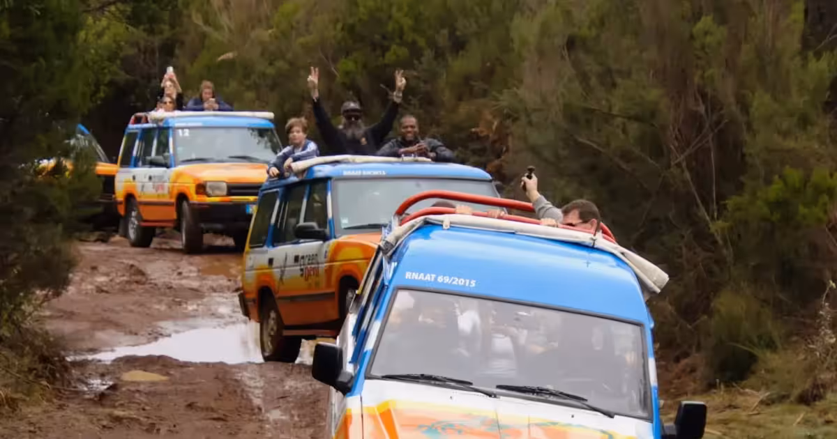 Open-roof 4x4 jeep crossing a mountain trail through Madeira laurel forest.