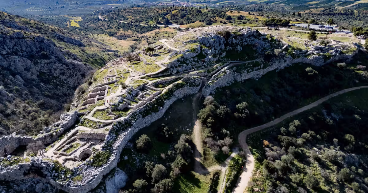 Ancient stone ruins of Mycenae citadel overlooking Peloponnese landscape.
