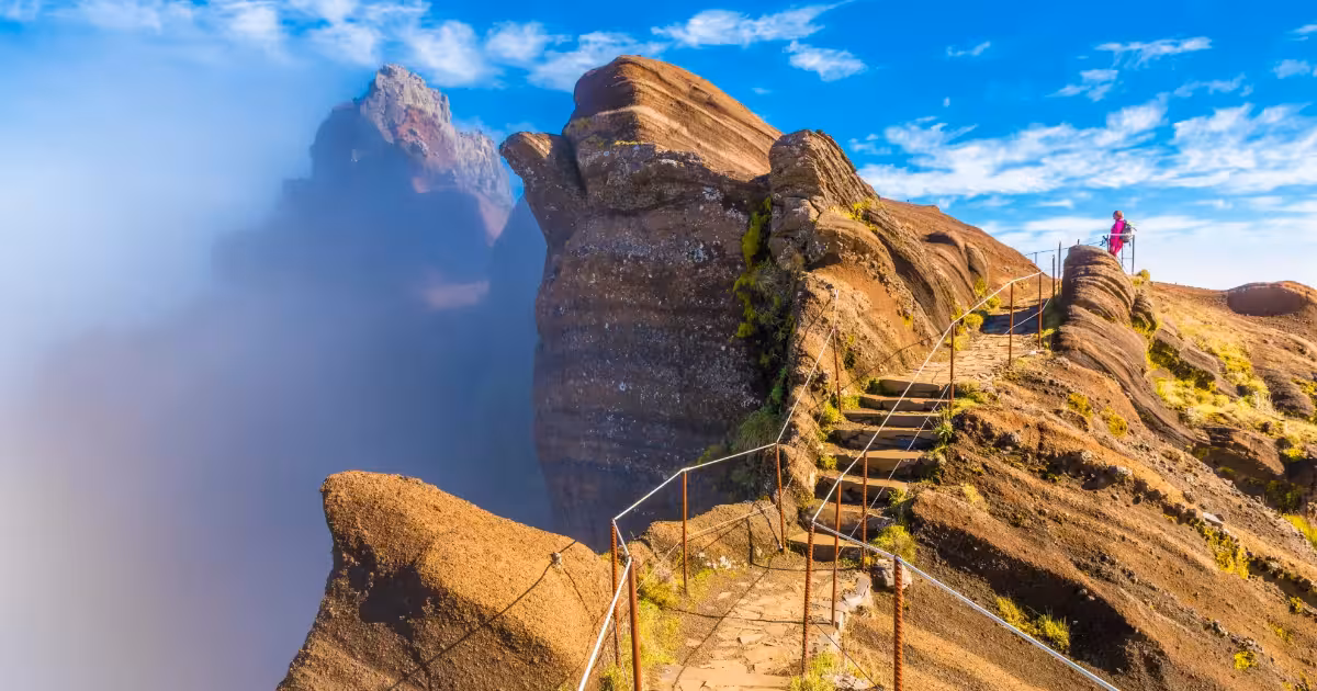 Hiker on the PR1 trail between Pico do Areeiro and Pico Ruivo at sunrise.