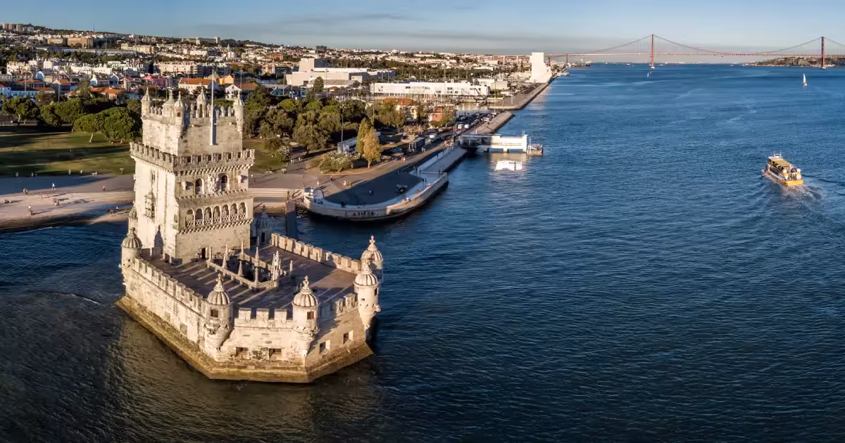 Turisti su un tour guidato in barca che passa davanti alla Torre di Belém sul fiume Tago