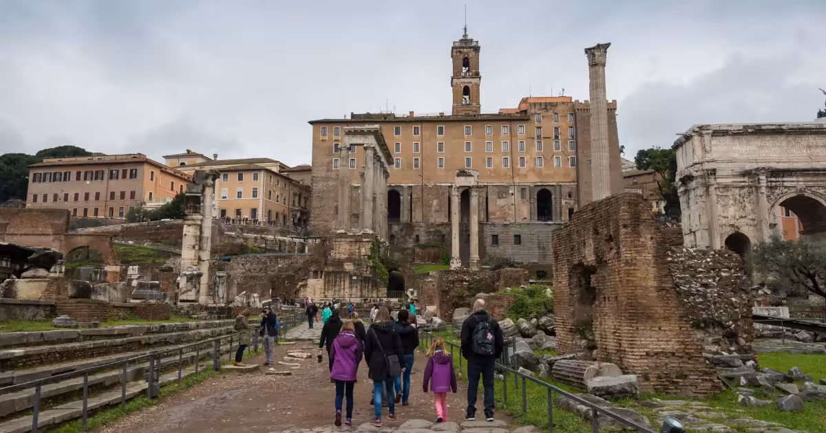 Guided walking tour group crossing a cobblestone street near the Roman Forum.