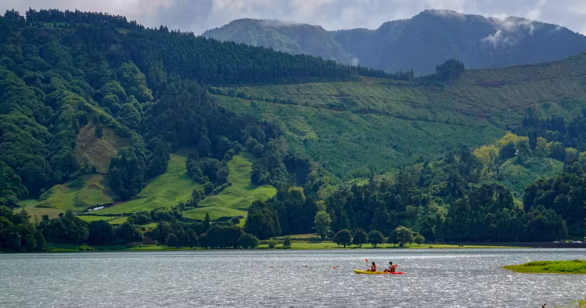 Kayaker paddling on Sete Cidades twin lakes surrounded by volcanic crater walls
