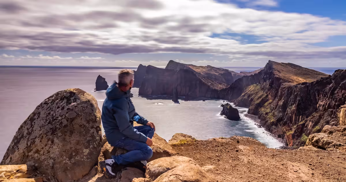 Solo hiker standing on misty Madeira cliffs overlooking the Atlantic Ocean