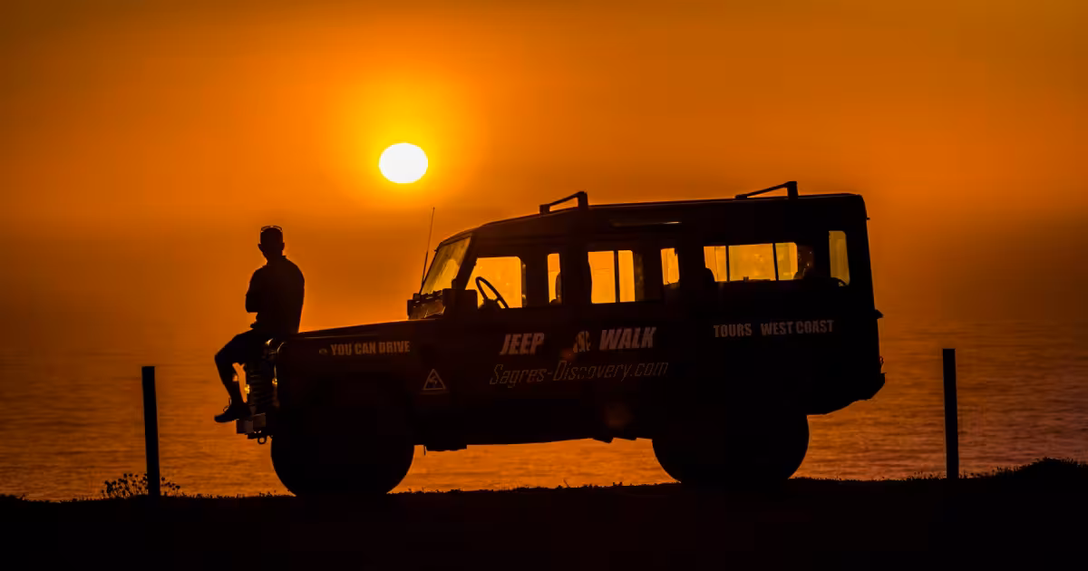 4x4 jeep on a dusty ridge overlooking the Algarve coastline at sunset