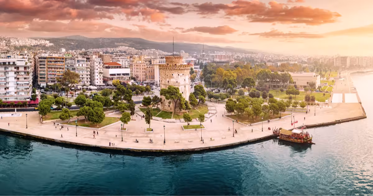 Historic White Tower of Thessaloniki with waterfront and Thermaik Gulf at sunset light.