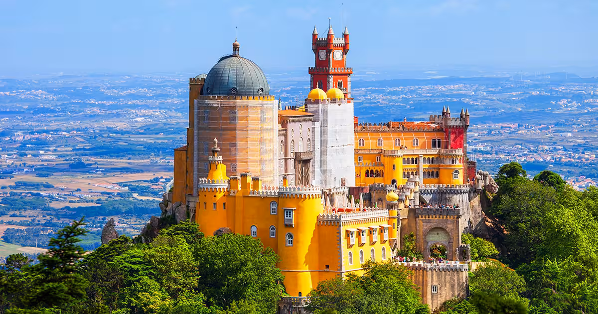 Pena Palace colorful turrets rising above mist-shrouded Sintra forest canopy