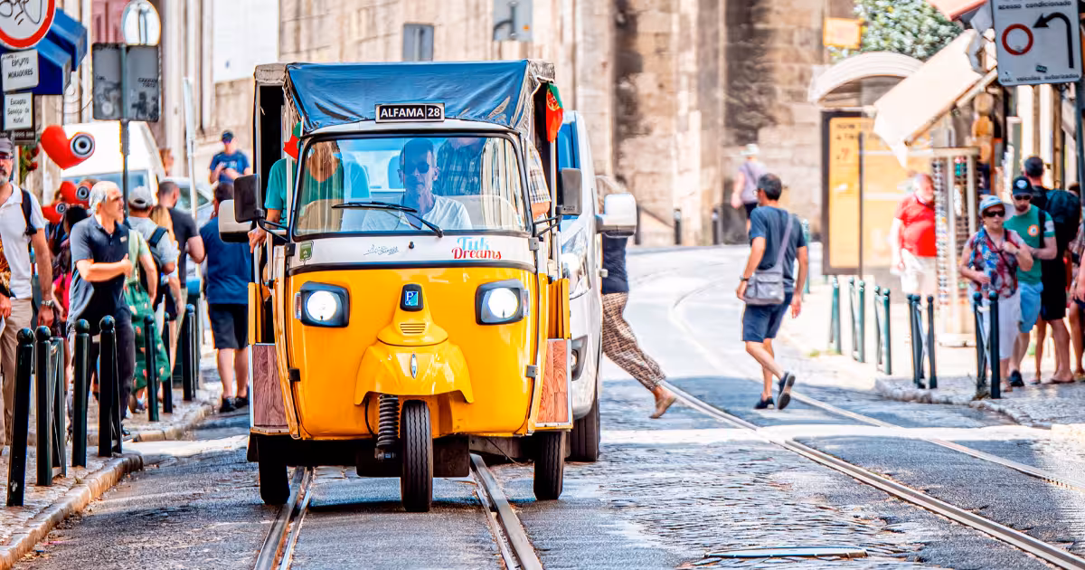 Electric tuk tuk navigating a narrow cobbled alley in Alfama Lisbon