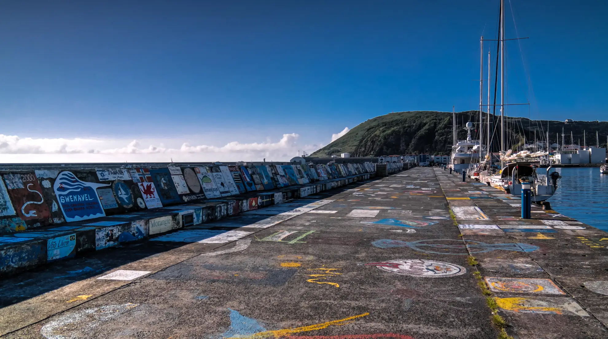 Colourful boat murals painted on the harbour wall of Horta Marina Faial Azores.