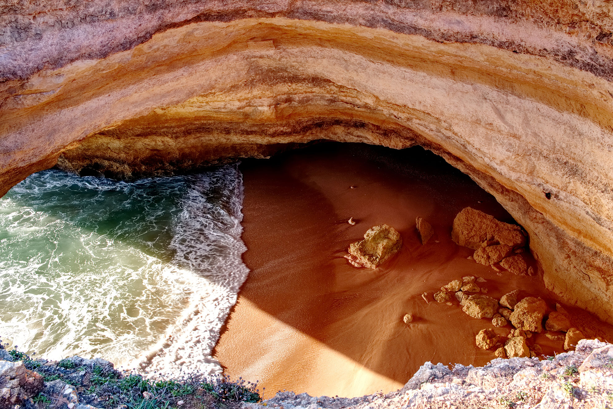 Benagil Cave entrance at high tide with waves surging through the limestone arch