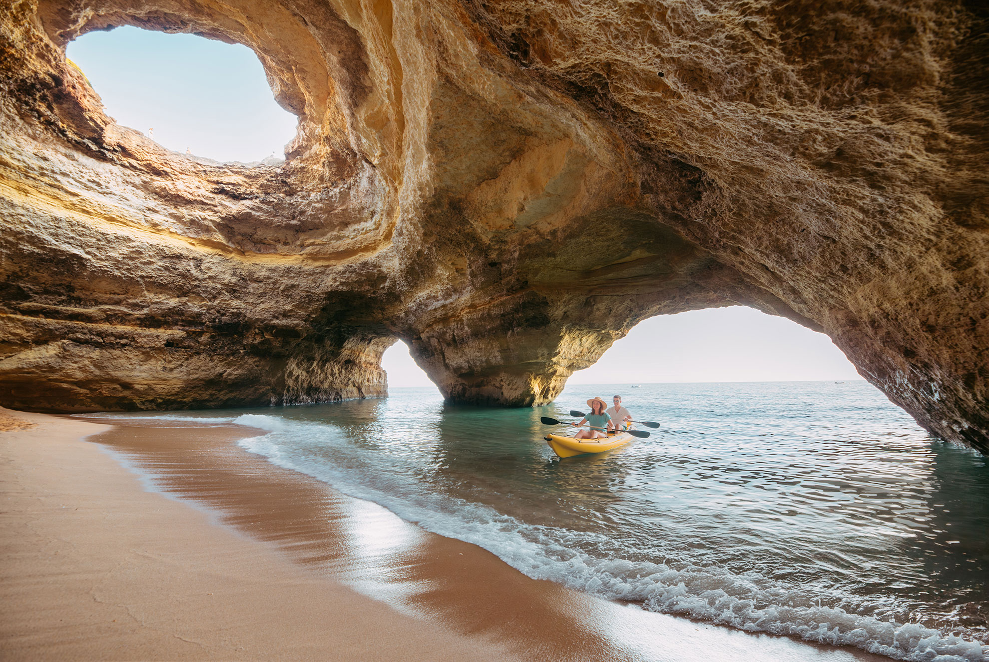 Kayaker approaching Benagil Cave cliffs in calm Algarve morning sea conditions