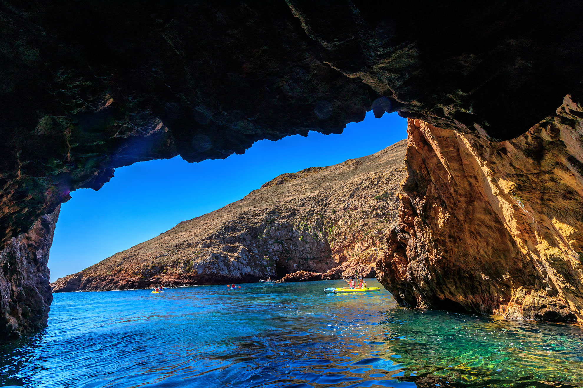 Small boat passing through the Furado Grande sea cave tunnel on Berlenga Island
