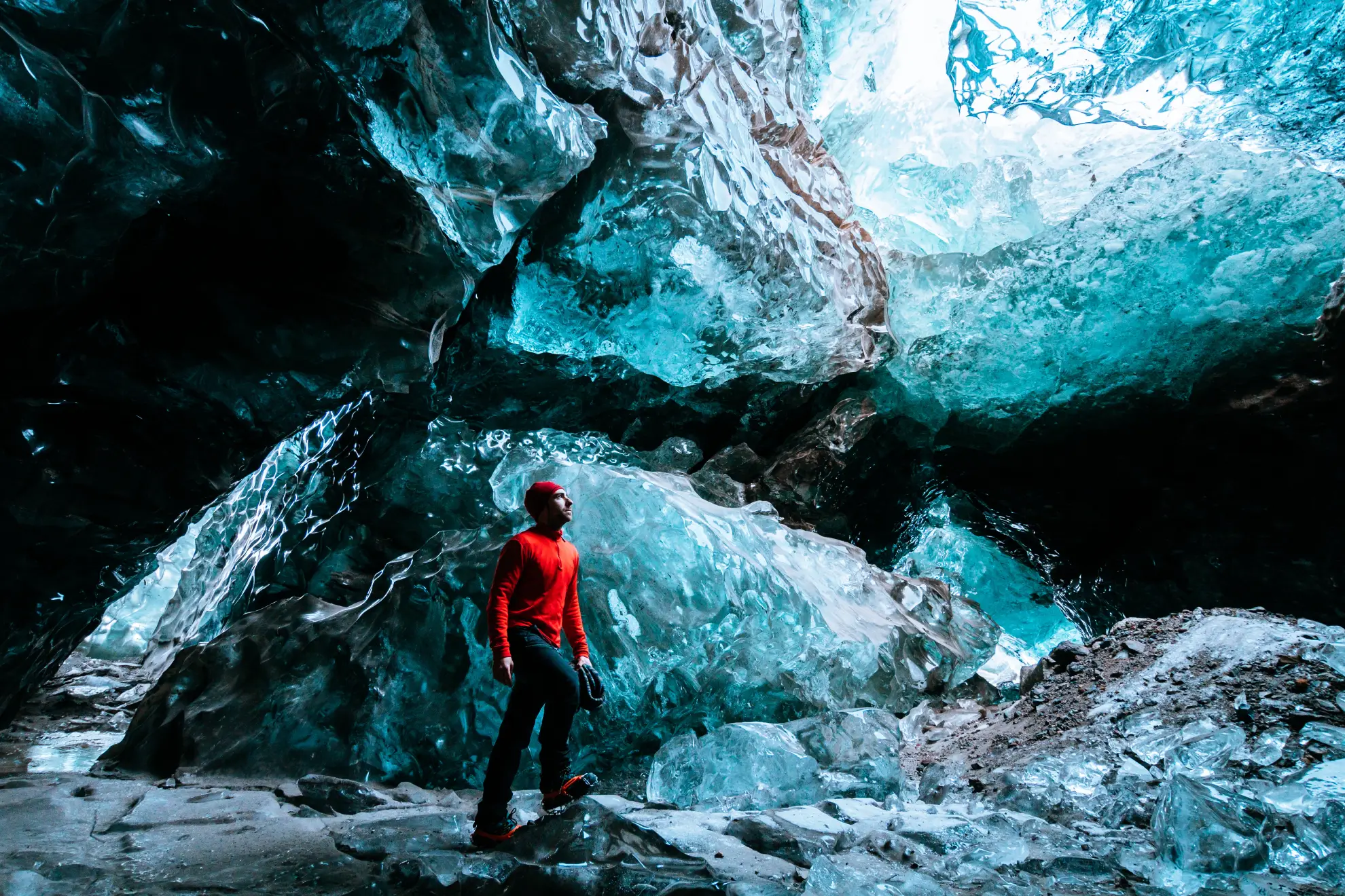 Alpinista all'interno di una grotta di ghiaccio blu nel ghiacciaio Vatnaj&ouml;kull con equipaggiamento di sicurezza e ramponi.