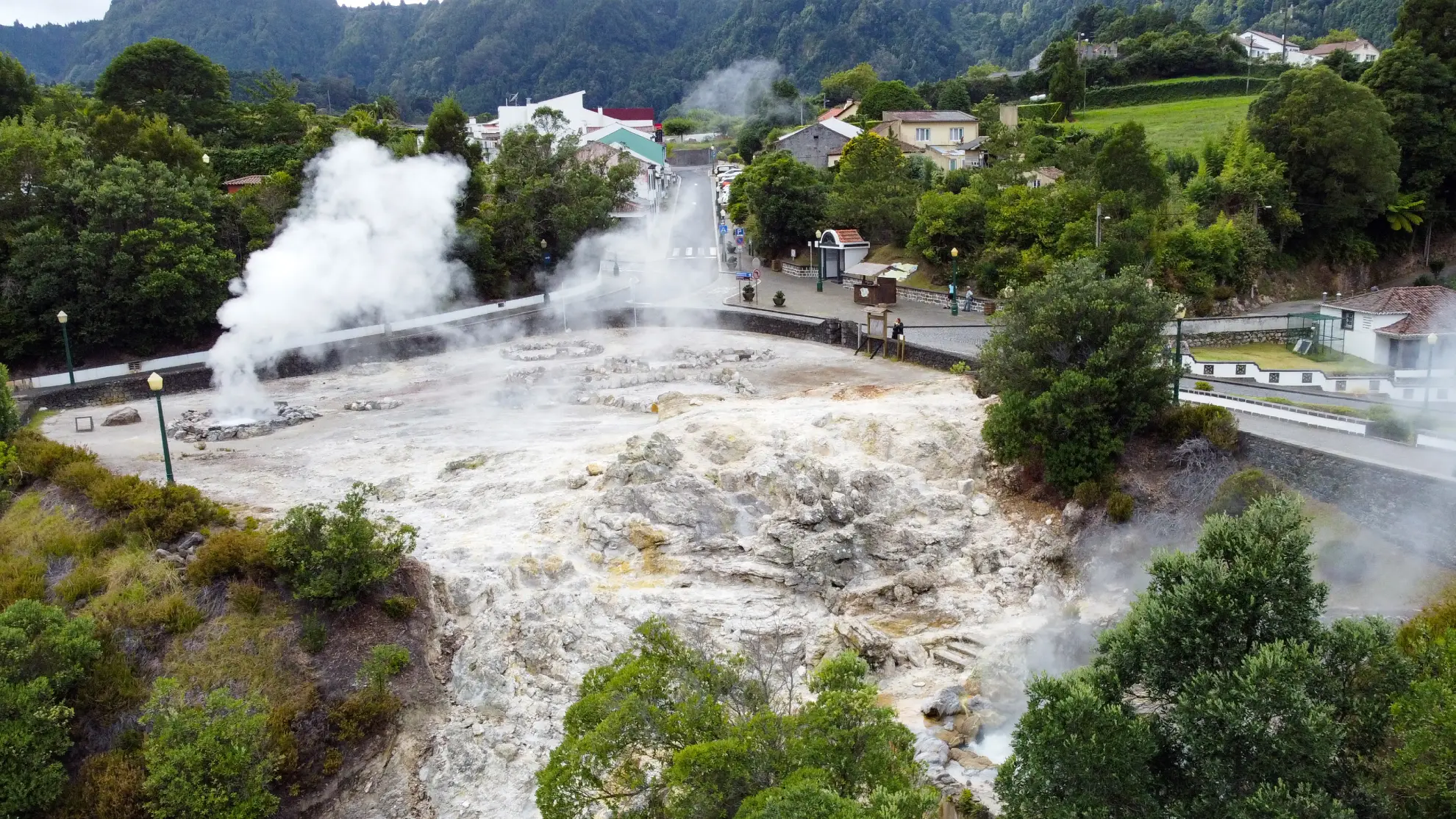 Active boiling mud caldeiras in the centre of Furnas village with visitors on boardwalk.