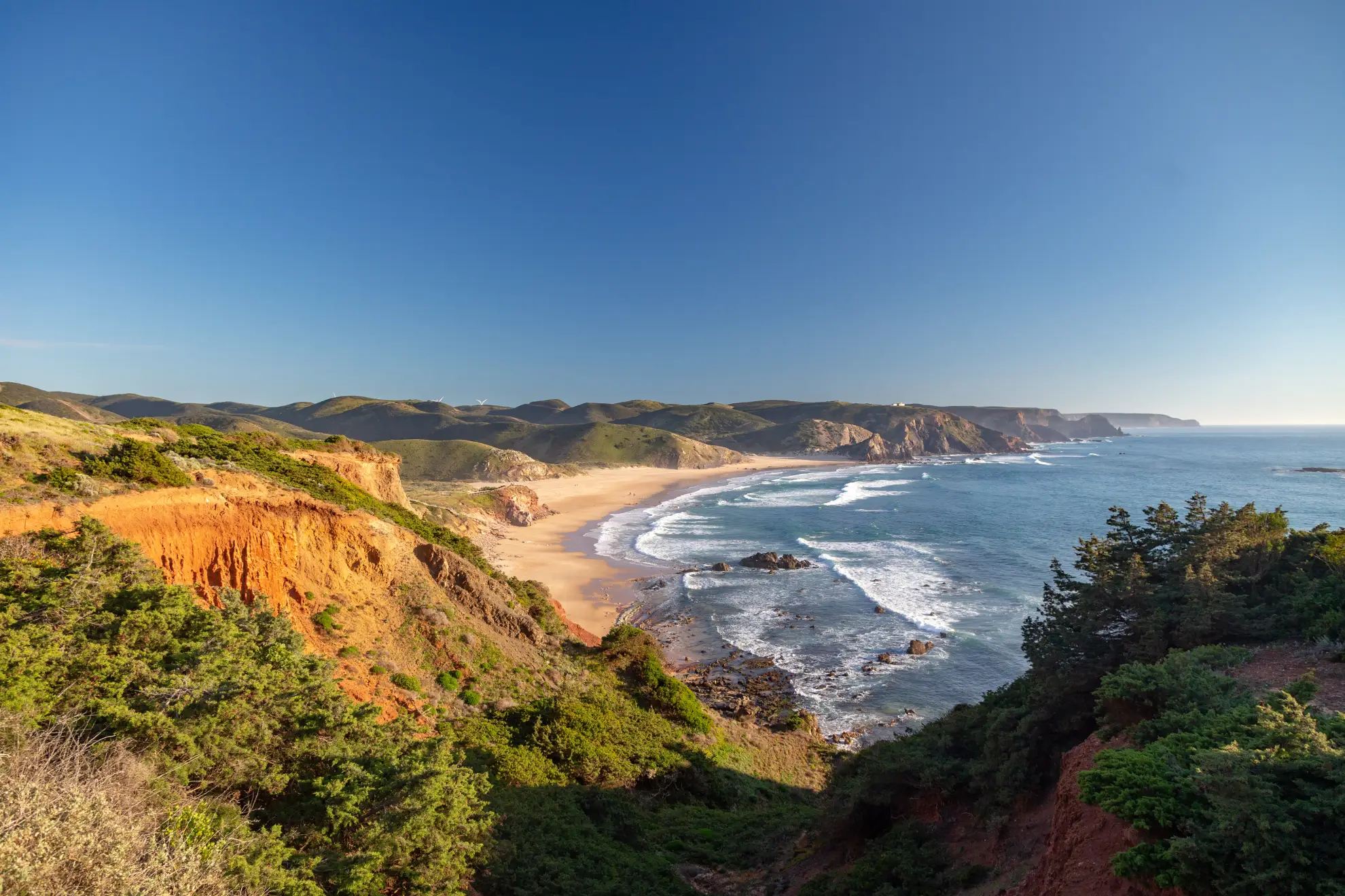 Ochre sea cliffs of Costa Vicentina at golden hour above Atlantic surf.