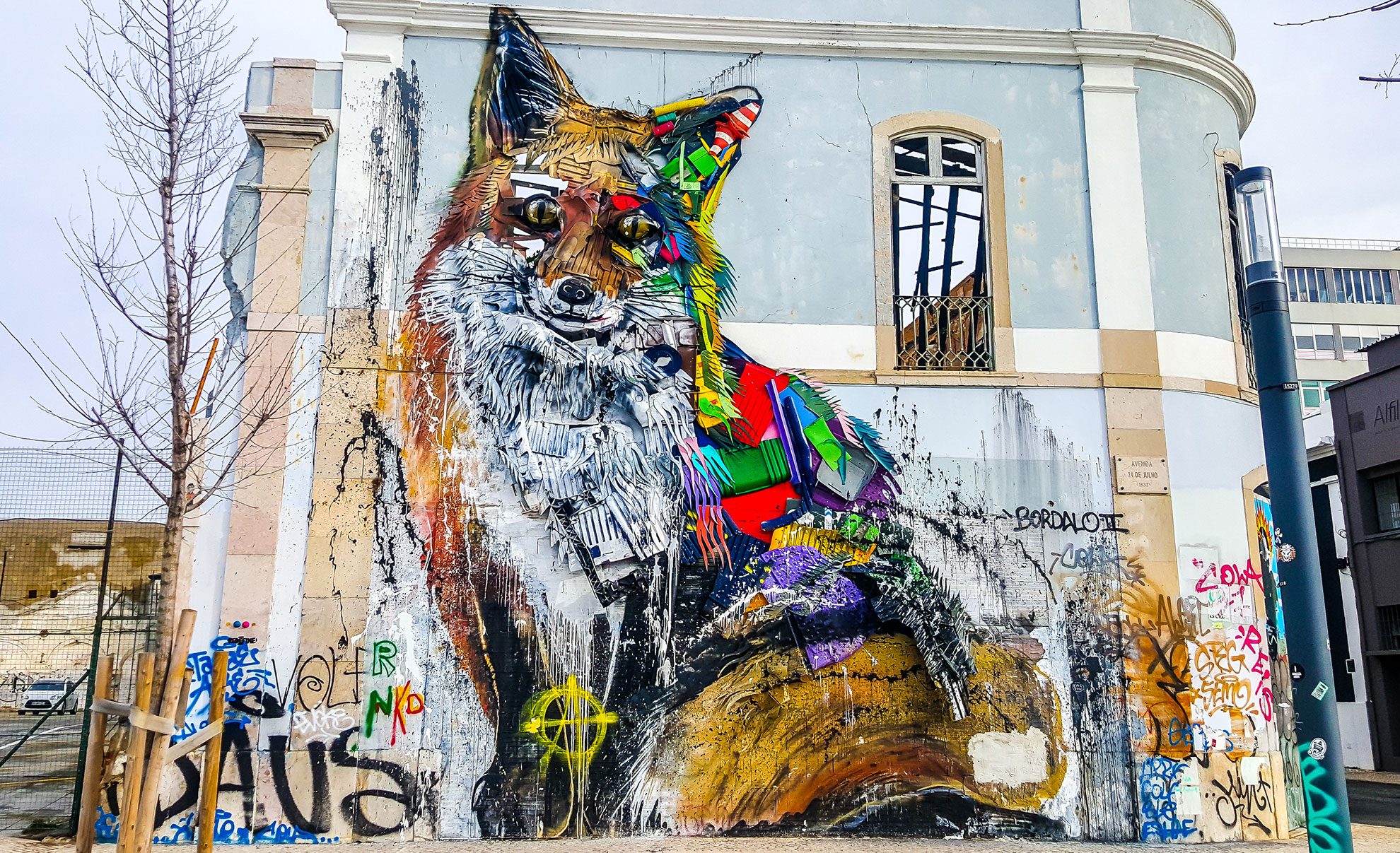 Large-scale Vhils mural on a warehouse facade in Lisbon's Marvila district.