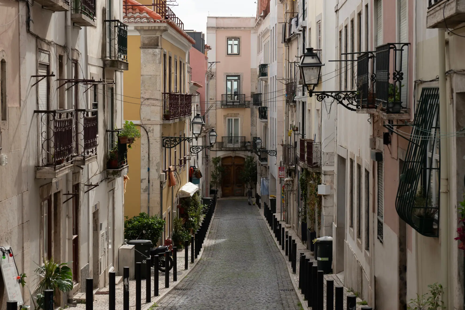 Narrow Mouraria street with fado heritage plaque and contemporary street art.
