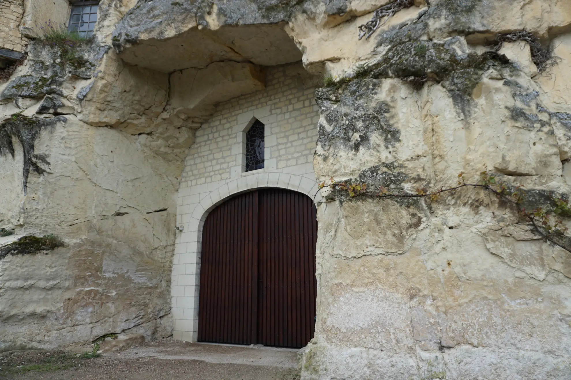 Stone-arched wine cellar interior with wooden barrel storage and limestone walls.