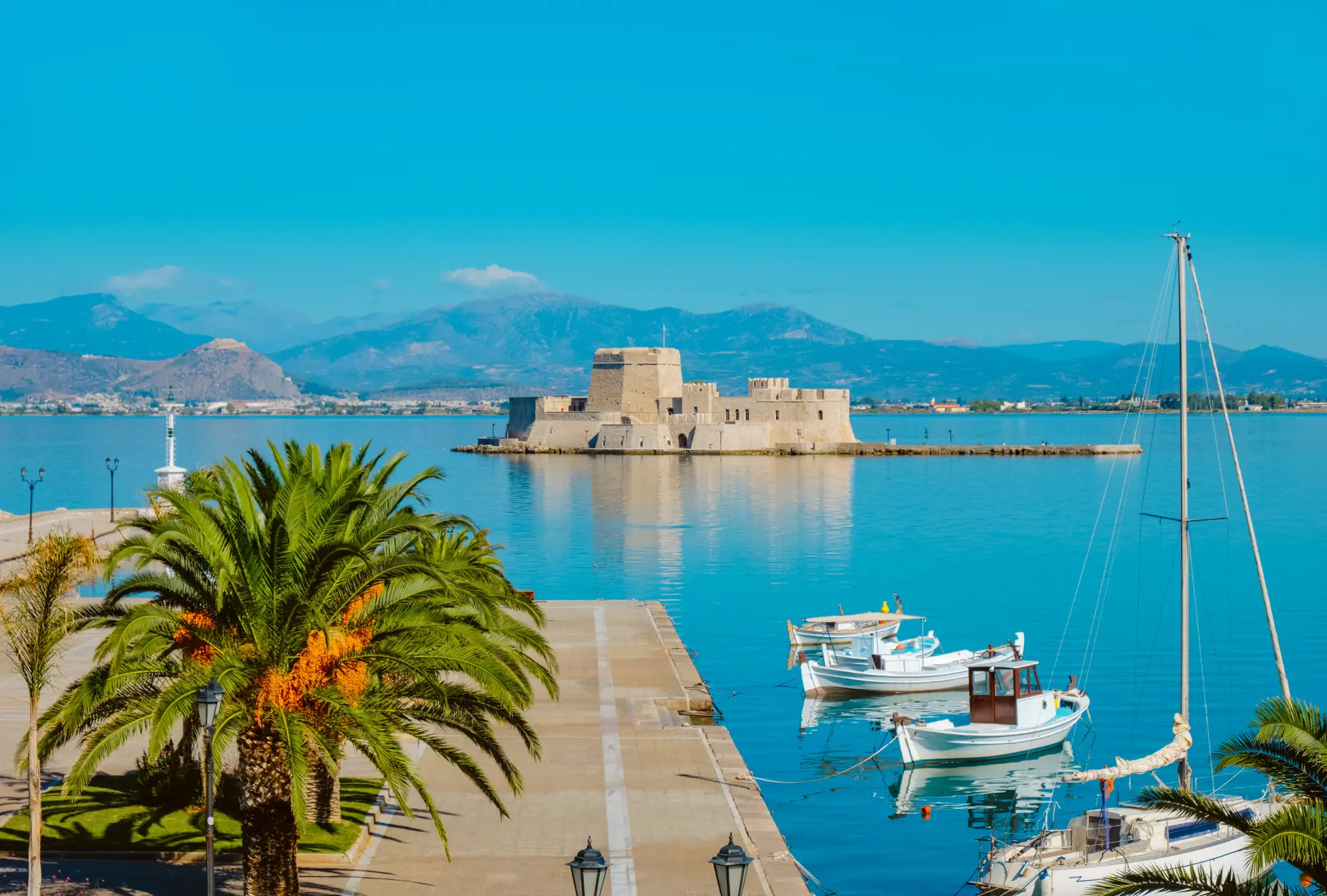 Nafplio harbour town with Palamidi fortress overlooking Mediterranean waterfront and neoclassical buildings.