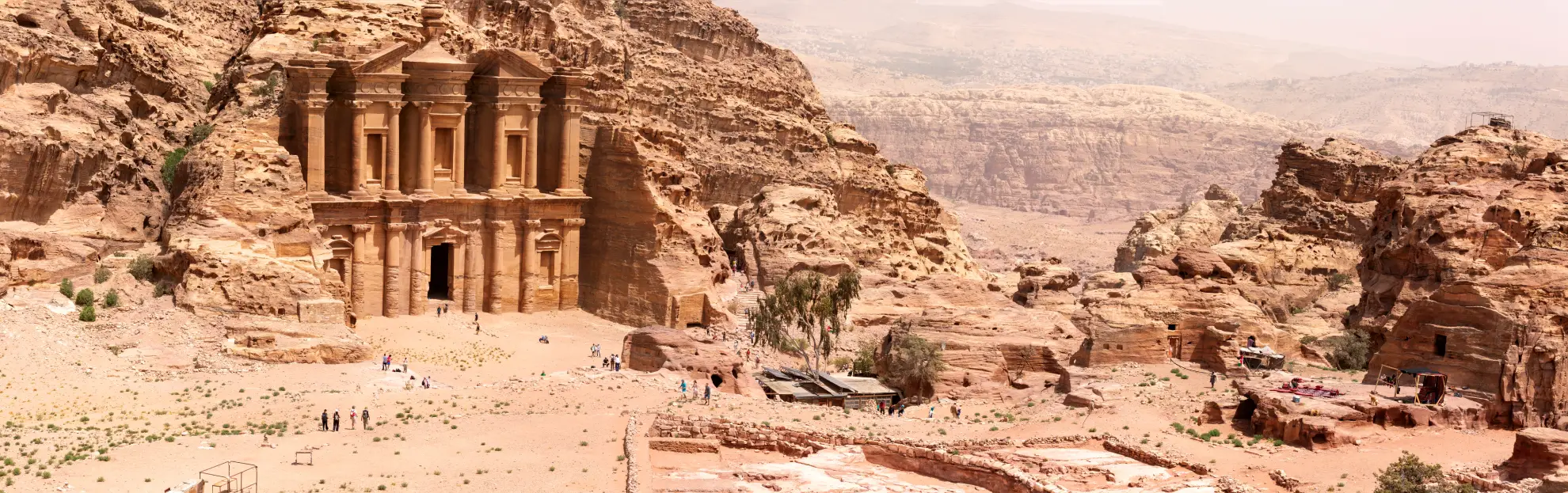 Panoramic dawn view of Petra's rose-red carved ruins across the valley.