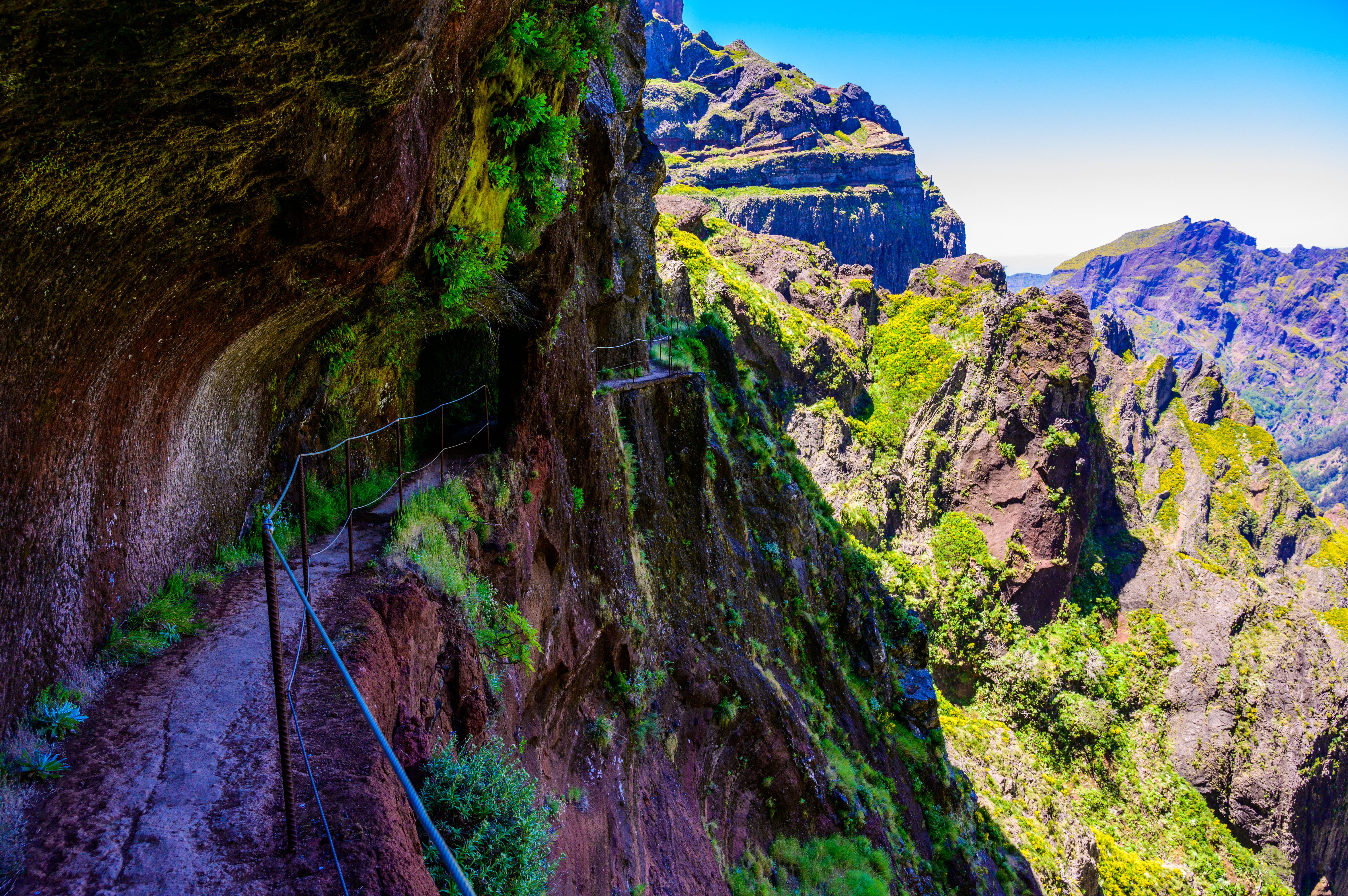Hiker entering a dark basalt tunnel on the Pico do Areeiro trail in Madeira.