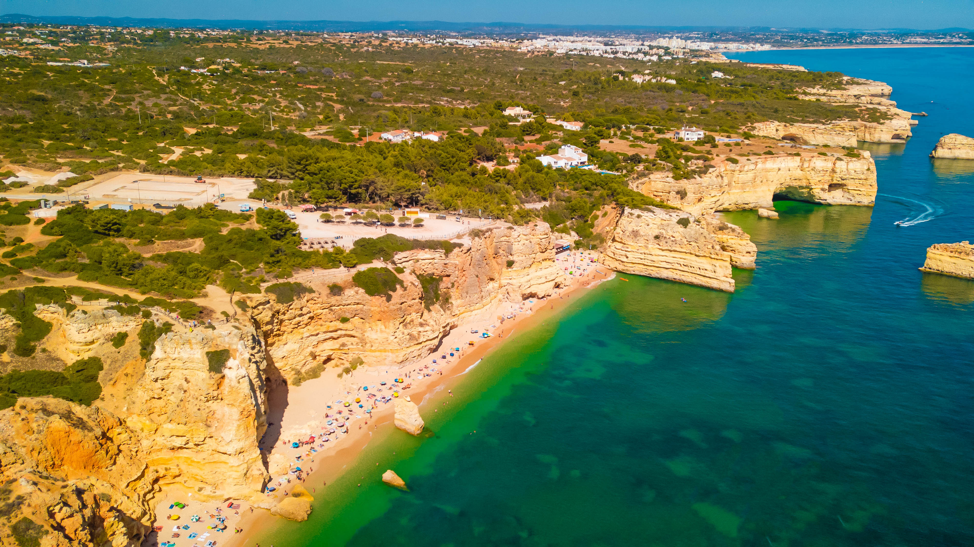 Honeycomb limestone terraces and clear coves at Praia da Marinha Algarve.