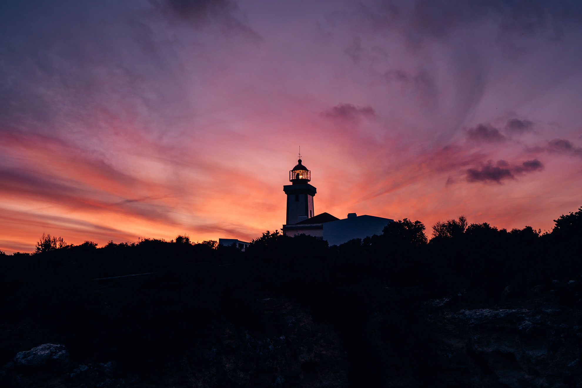 Alfanzina Lighthouse on the Algarve headland viewed from the Seven Hanging Valleys trail at sunset
