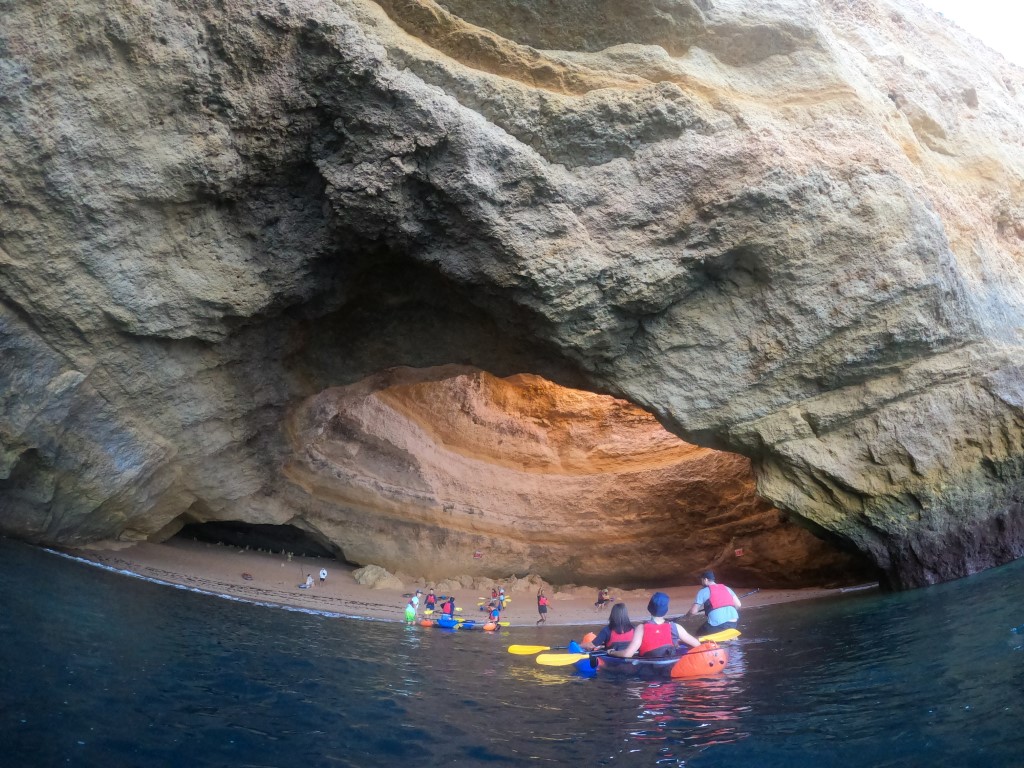 Two kayaks on calm mirror-like water at the Benagil Cave entrance at dawn