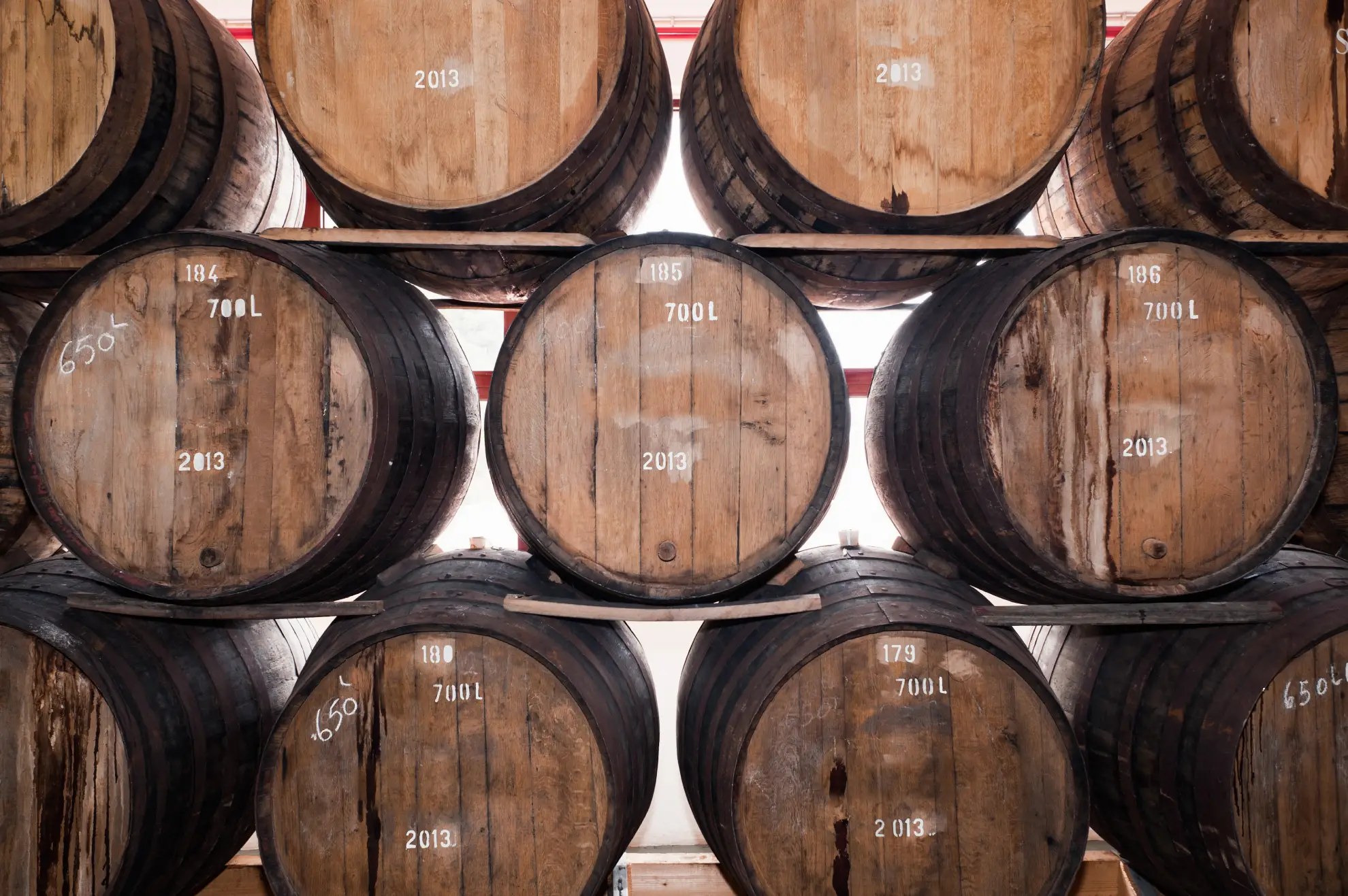 Aged oak wine barrels stacked in a traditional Madeira wine cellar.