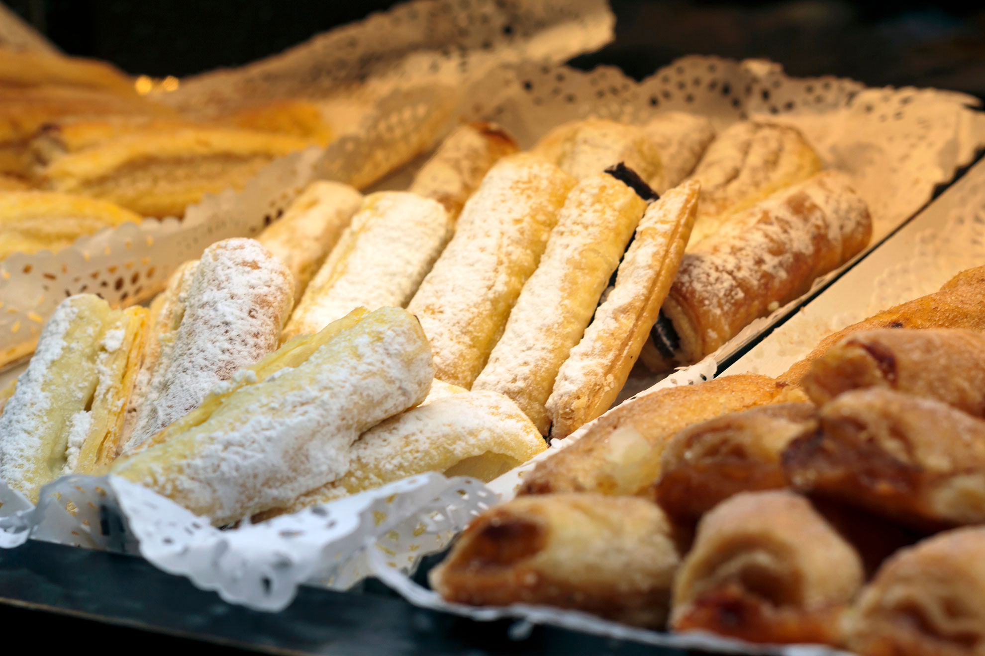 Sintra pastelaria window displaying Travesseiro pastries and Queijadas on cobblestones