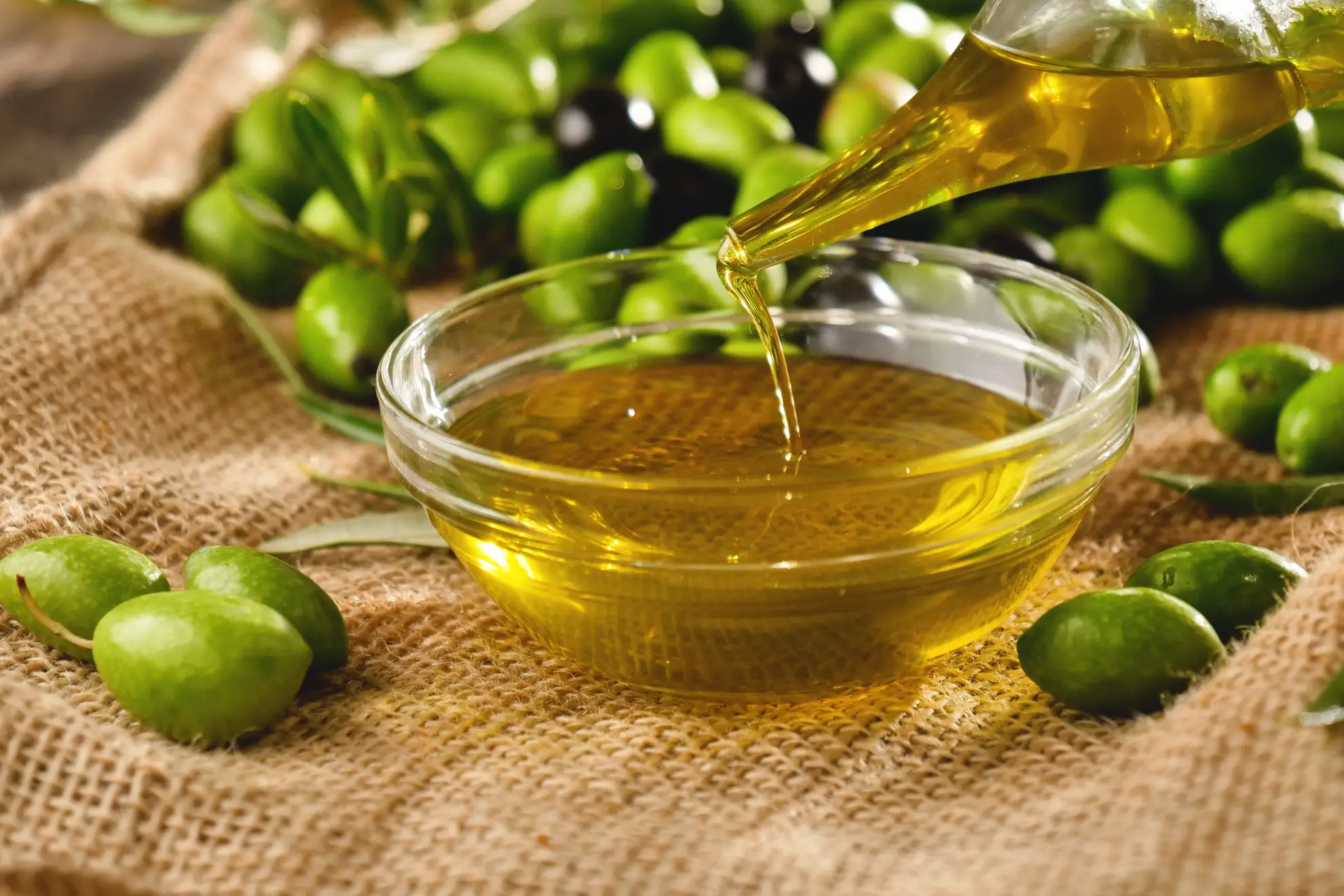 Fresh Tuscan extra virgin olive oil being poured onto a tasting plate at a farm.