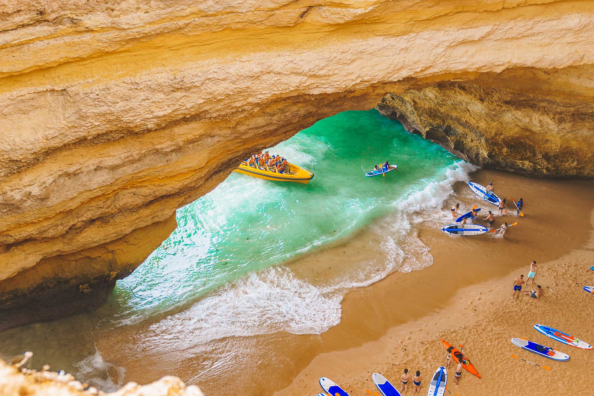 RIB boat and catamaran side by side near Algarve limestone sea cave entrance.