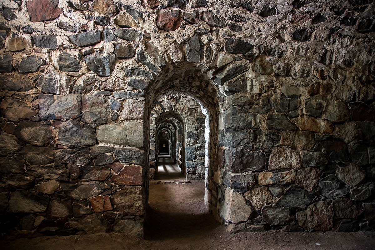 A dimly lit underground tunnel at Suomenlinna, showcasing stone walls and eerie passageways.